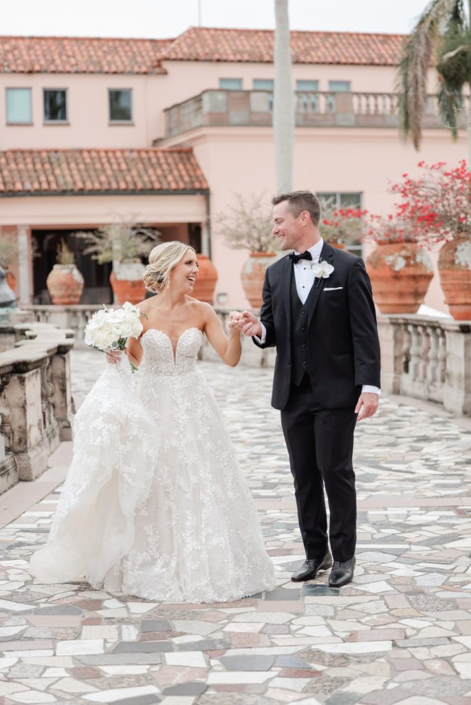 Newlyweds holding hands and laughing on Mediterranean-style courtyard terrace with terracotta tiles