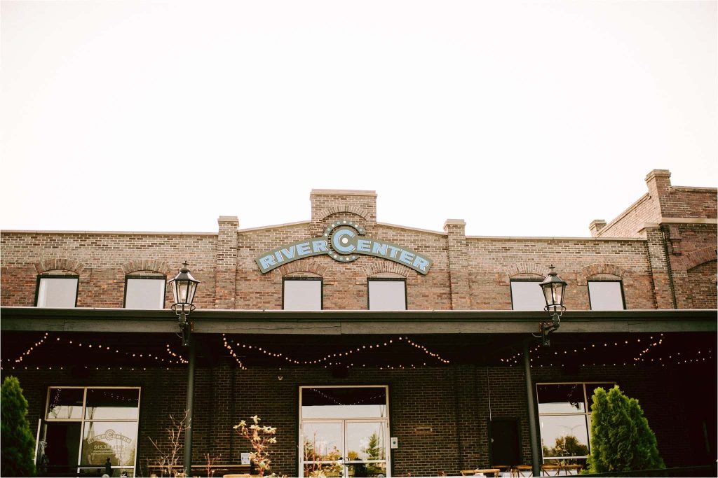 Historic brick River Center building exterior decorated with string lights for a wedding venue