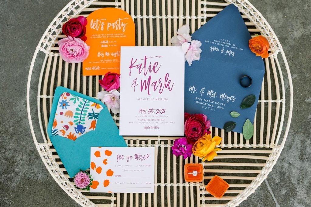 Colorful wedding invitation suite with vibrant blooms arranged on striped wicker tray