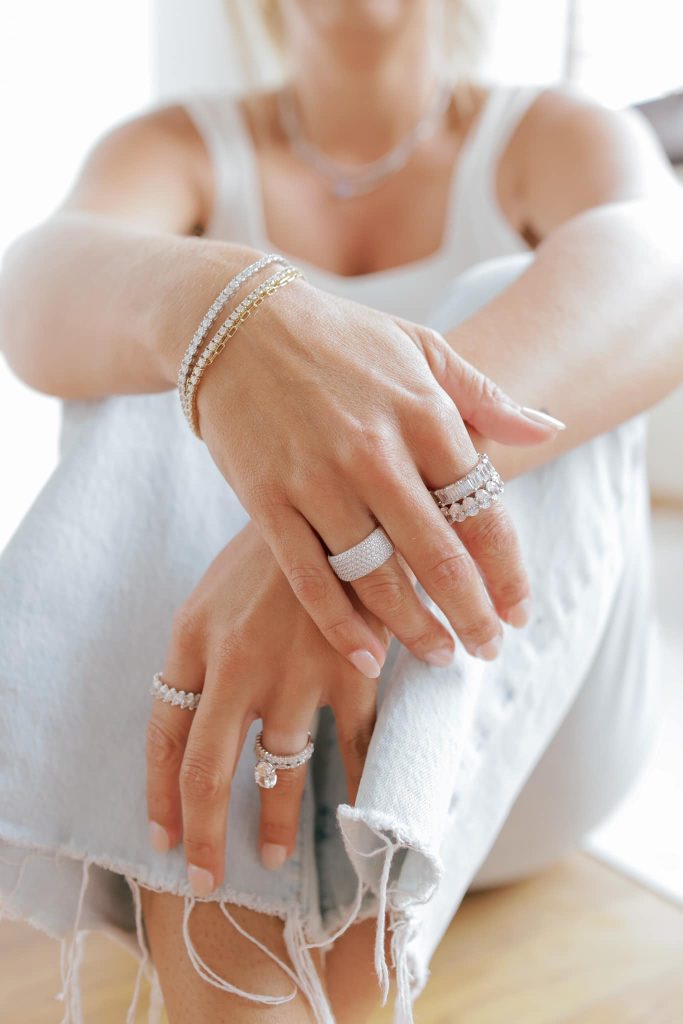 Bride displaying diamond wedding bands and engagement rings on both hands while wearing white dress