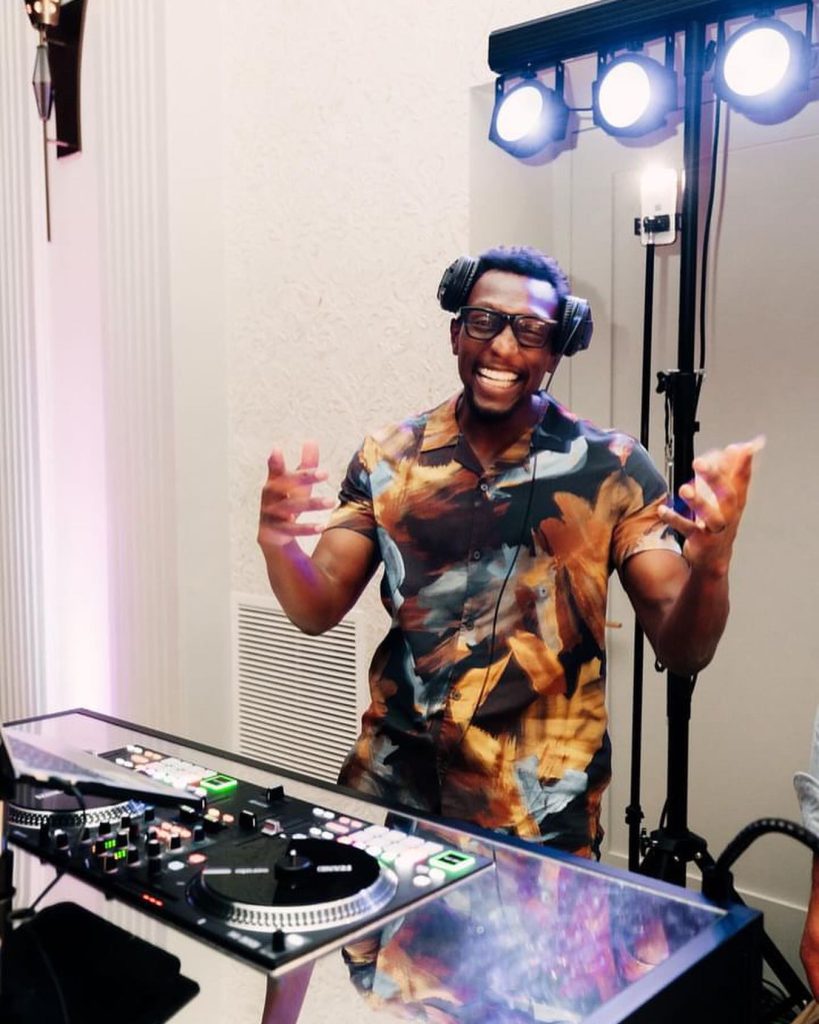 DJ wearing headphones gestures enthusiastically behind turntables at reception