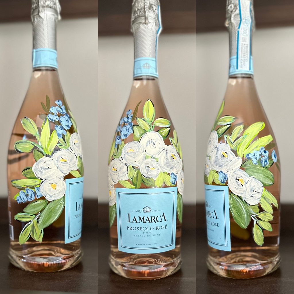 Three rose wine bottles hand-painted with white blooms and blue flowers with green leaves for wedding celebration