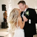 Newlyweds share their first dance surrounded by sparkling string lights in modern reception venue