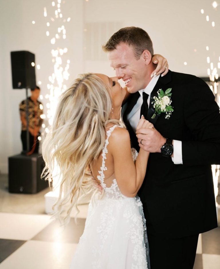 Newlyweds share their first dance surrounded by sparkling string lights in modern reception venue