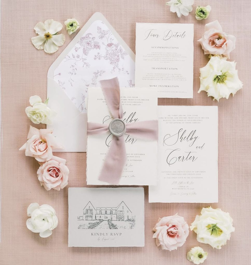 Elegant wedding invitation suite in blush tones with calligraphy, floral liner, and fresh blooms
