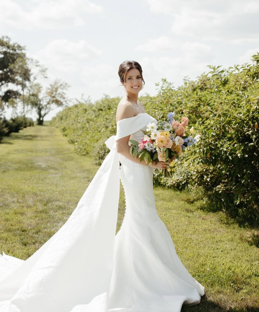 Bride in off-shoulder gown holding colorful bouquet in garden setting
