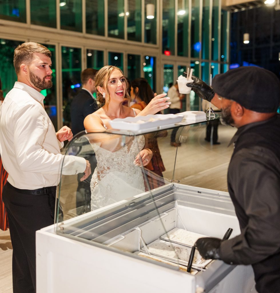 Bride and groom serving gelato to wedding guests from display case