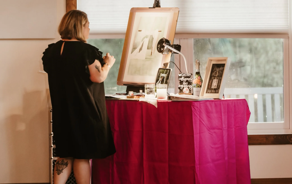 Live artist painting on easel at reception entertainment station