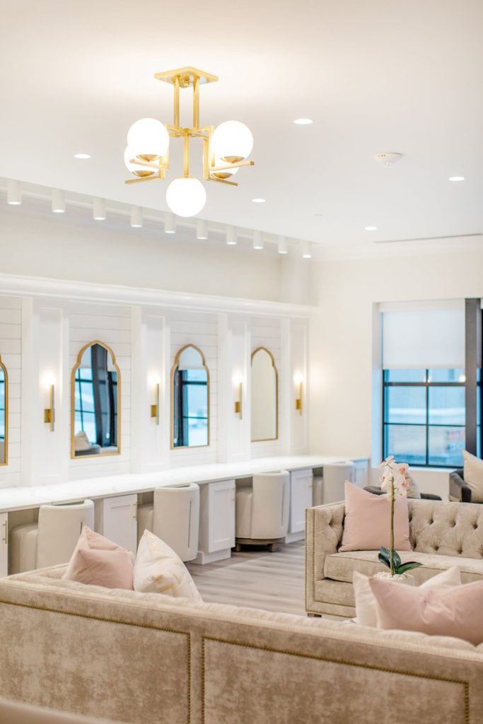 Elegant bridal suite with white velvet seating, arched mirrors, gold accents, and modern chandelier