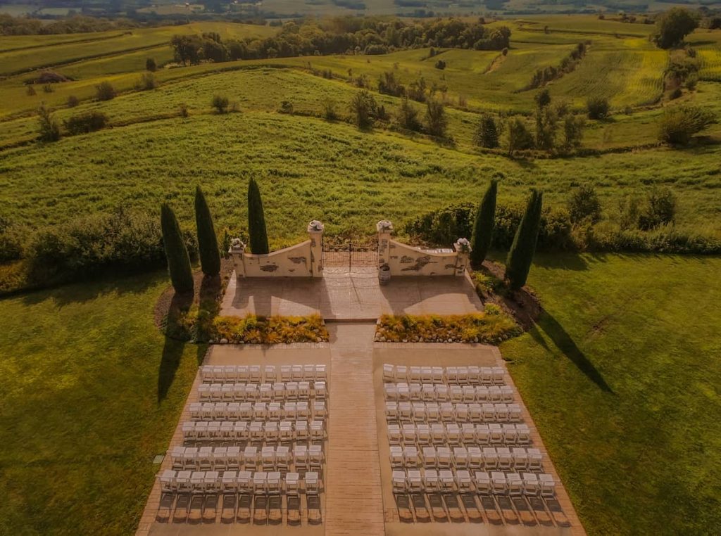 Aerial view of outdoor ceremony space with decorative archway overlooking Iowa farmland