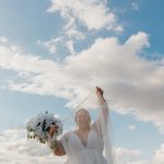 bride smiling through her veil in the sky