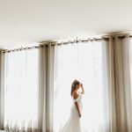 bride in wedding dress near window