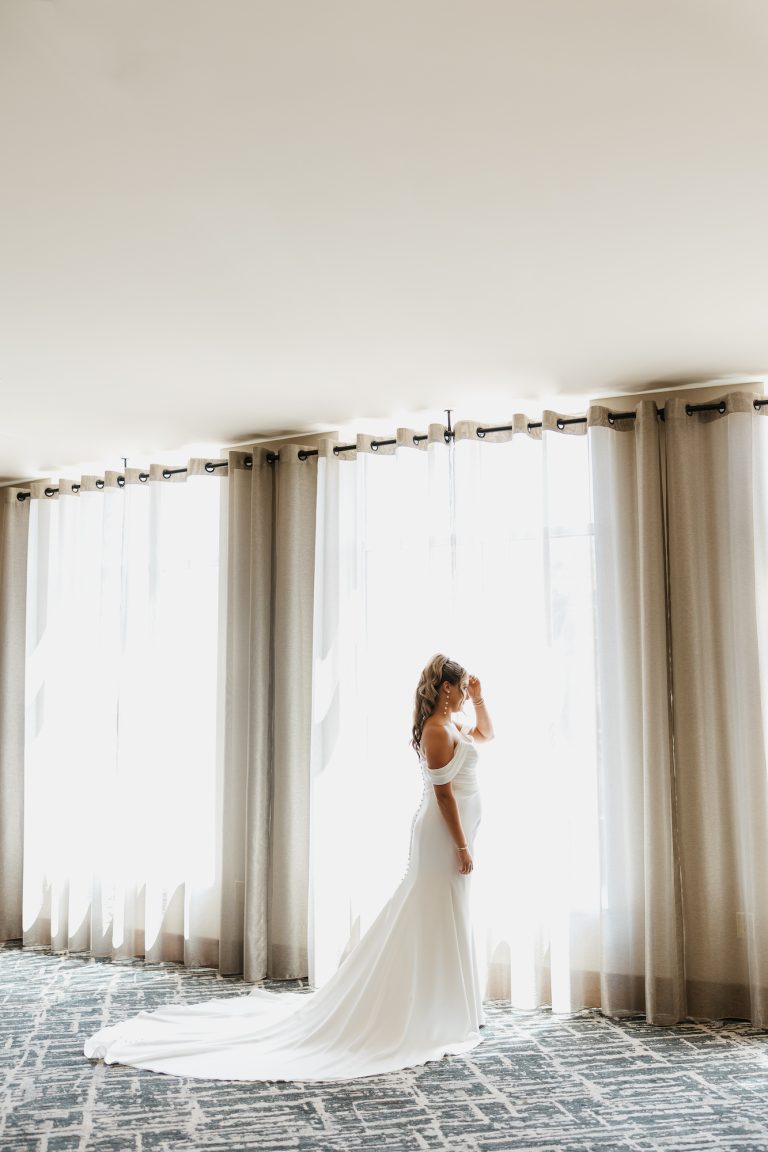 bride in wedding dress near window