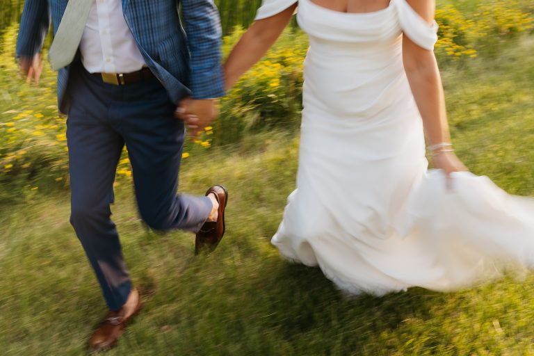 bride and groom holding hands and running