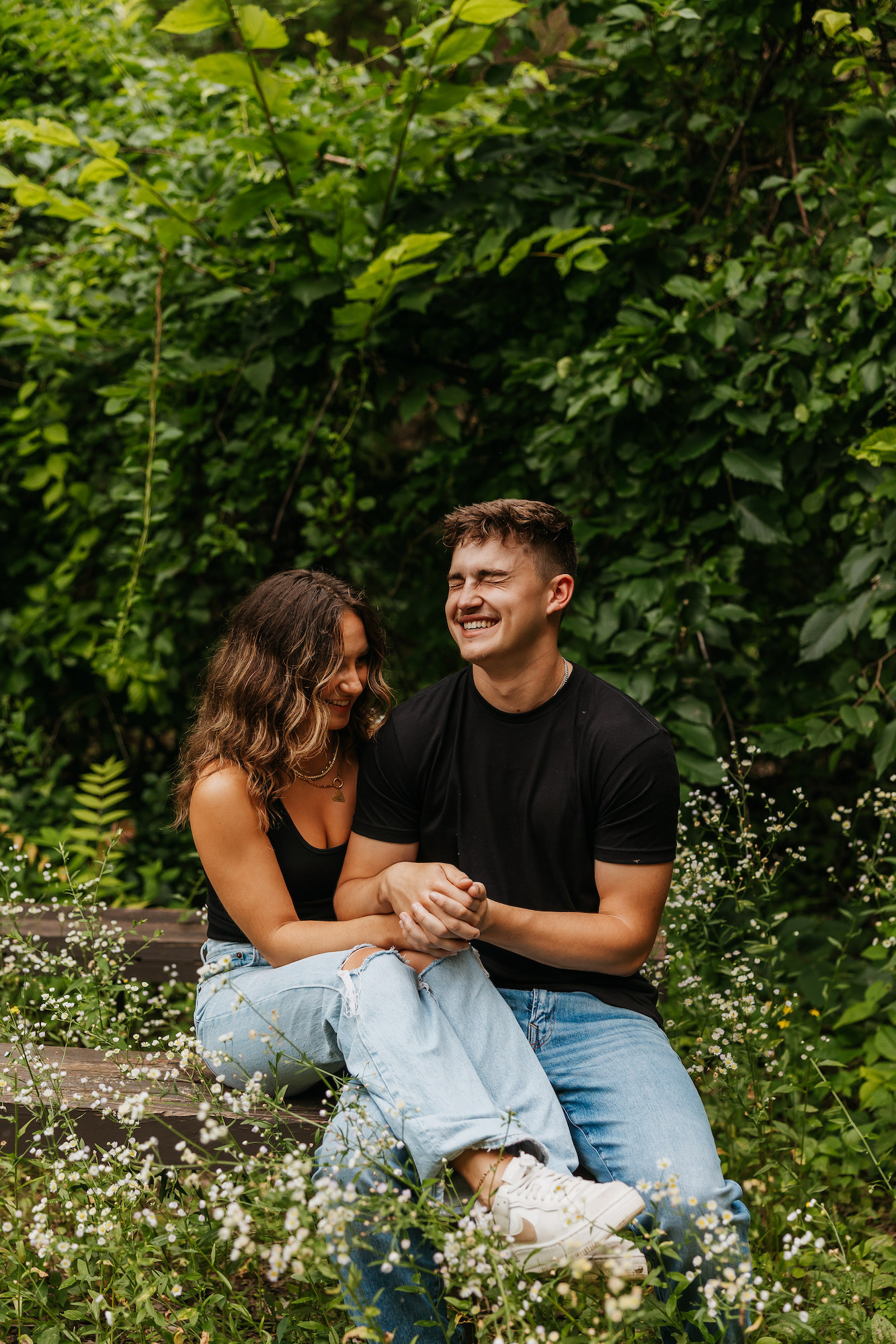 couple holding hands and laughing on a bench outdoors