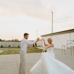 groom giving bride a spin in her wedding dress at sunset