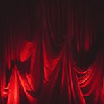 Dramatic red velvet stage curtains illuminated with theatrical lighting