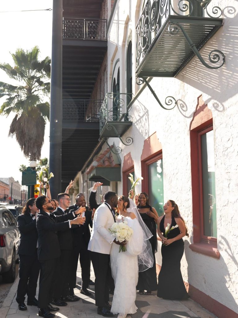 Couple kissing outside of venue with wedding party