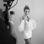 Bride in feathered mini dress poses during bridal boutique photoshoot