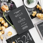 Modern black and white invitation suite with table number and yellow blooms on floral printed tablecloth
