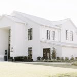 Modern white farmhouse-style venue with black-framed windows and manicured landscaping in Houston