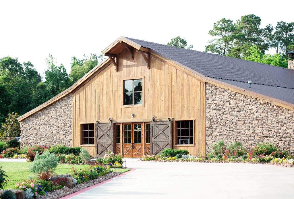 Rustic barn venue with stone walls, wood siding, and landscaped gardens