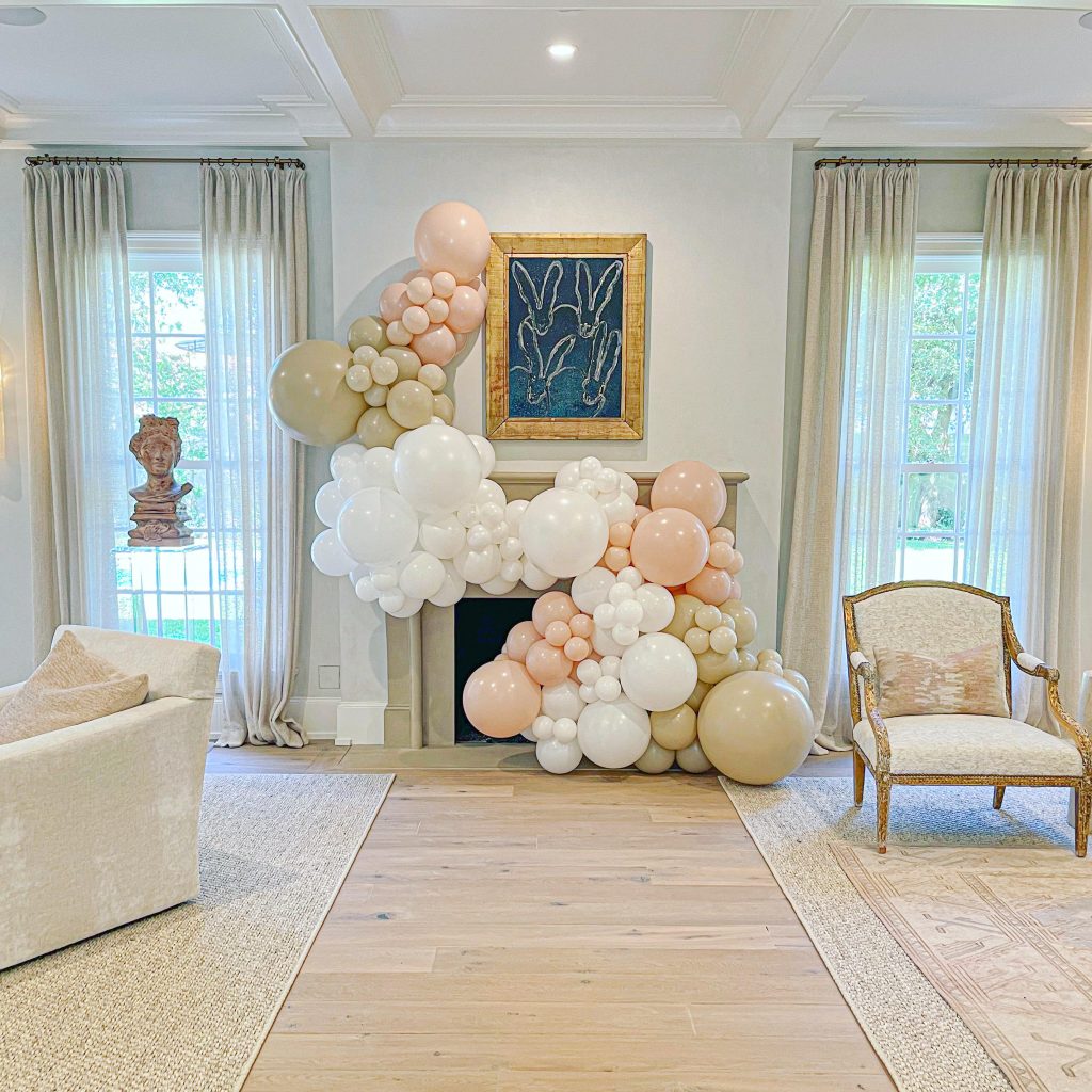 Elegant balloon garland installation in blush, cream, and gold tones framing fireplace mantel