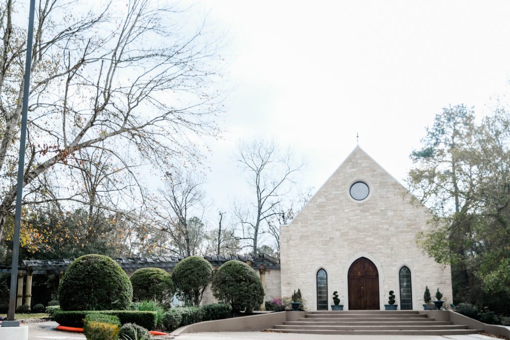 Stone chapel exterior at Ashton Gardens with manicured courtyard and arched entrance in North Houston