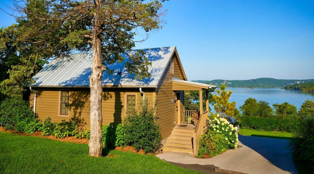 Lakeside cabin venue with metal roof and covered porch overlooking serene water views and green hills