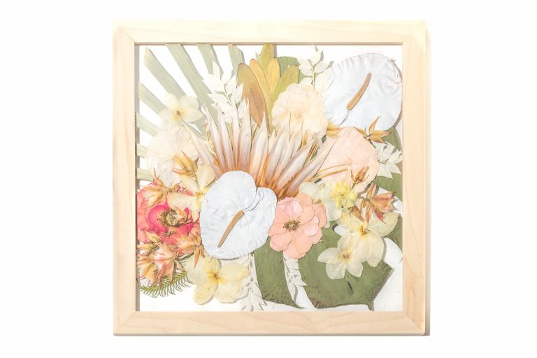 Framed pressed wedding bouquet with pastel flowers and tropical leaves in light wood shadowbox