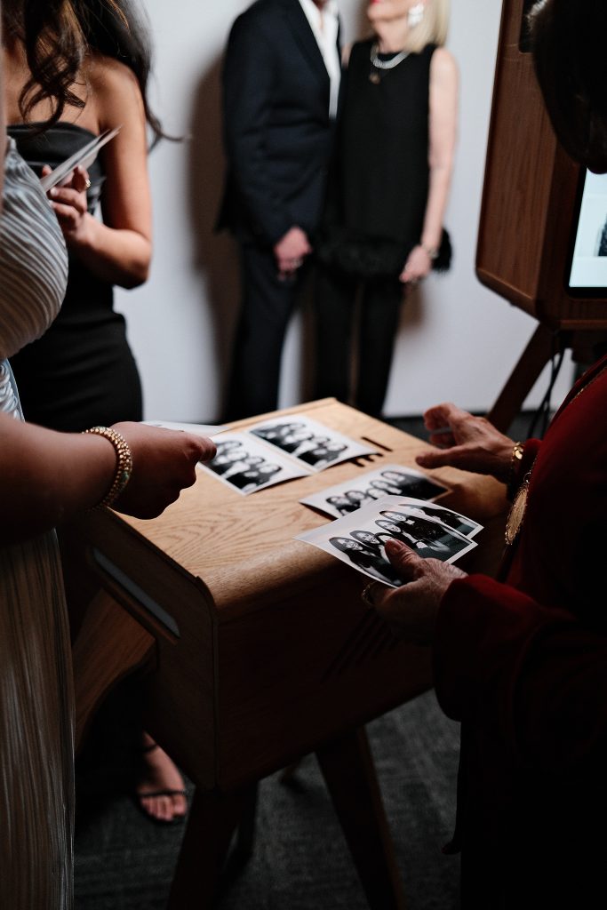 Wedding guests reviewing photo booth prints at reception