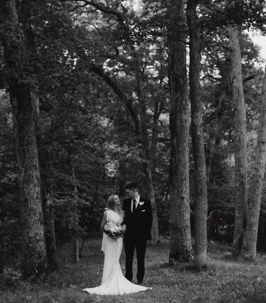 Bride and groom embrace in wooded forest setting