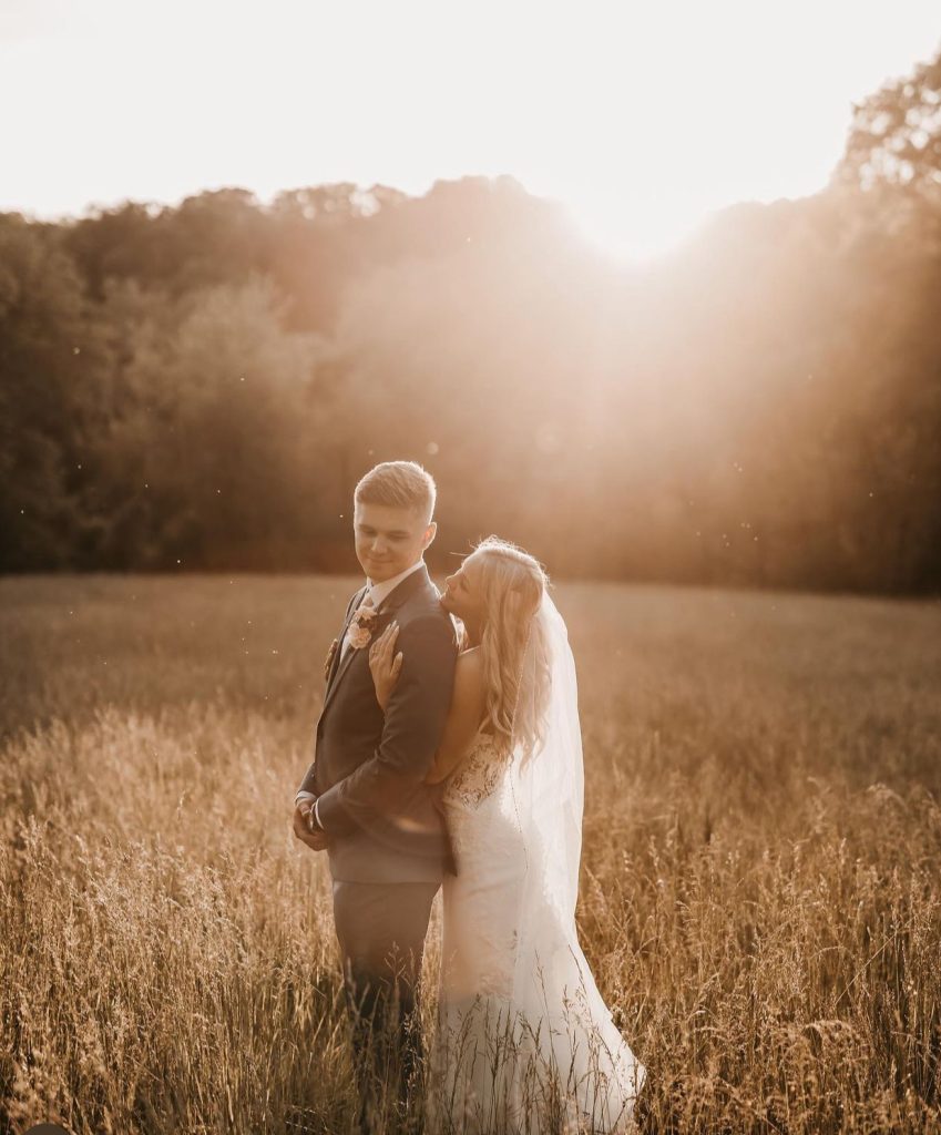 Bride and groom embrace in golden hour sunlight in Iowa prairie field