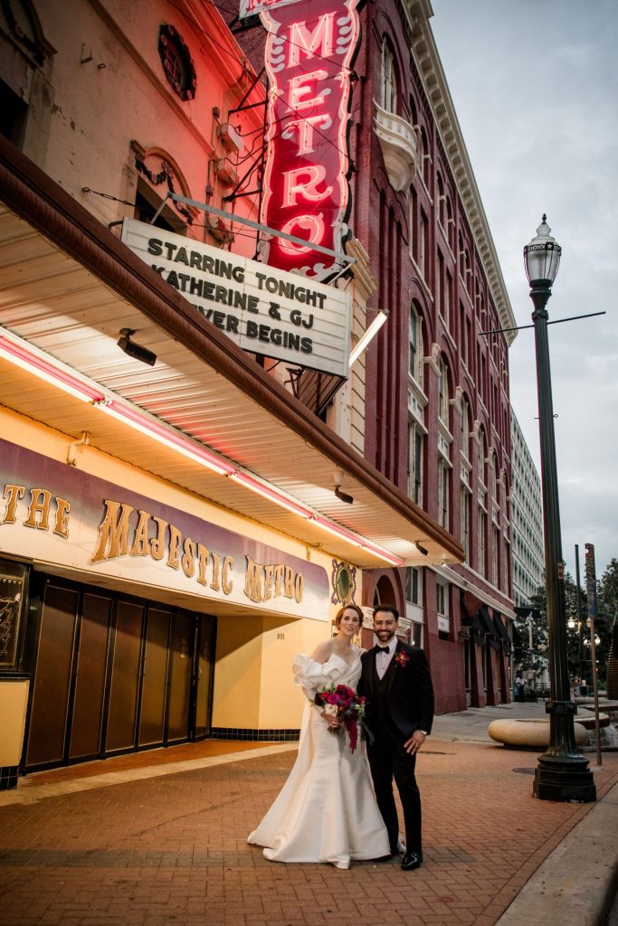Bride and groom pose outside historic Metro Theatre with illuminated marquee displaying their names