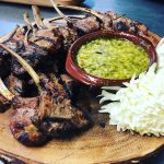Grilled lamb chops with chimichurri sauce on wooden serving board