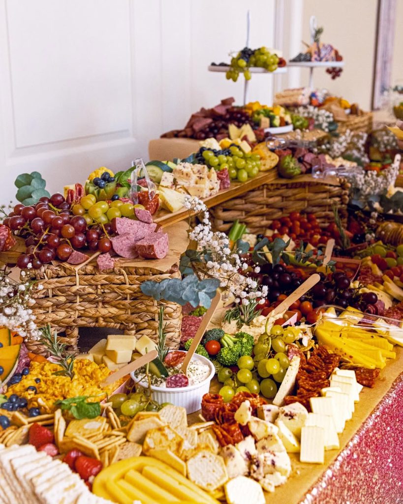 Elegant charcuterie spread with assorted cheeses, cured meats, grapes, crackers, and fresh garnishes on wooden boards