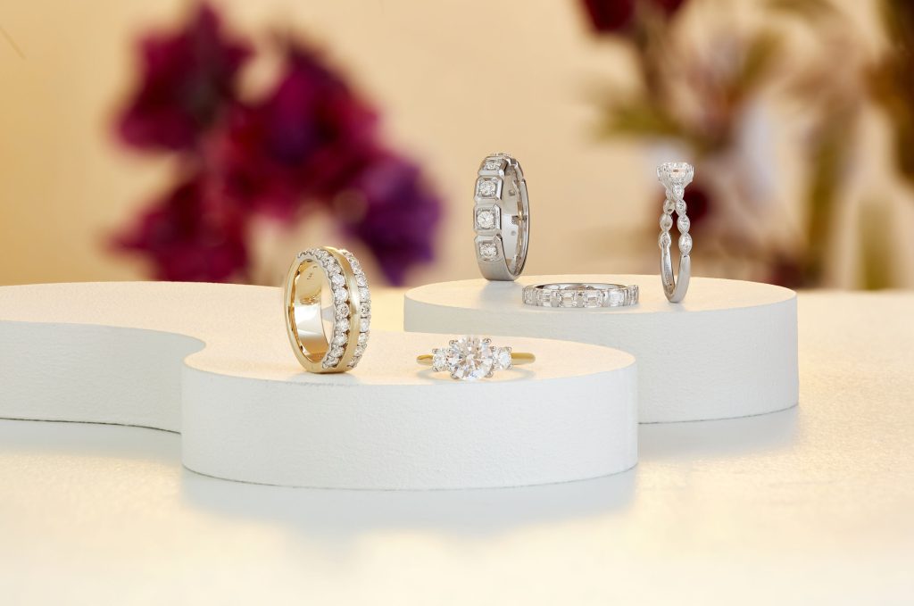 Collection of diamond and gemstone rings and earrings displayed on white pedestal