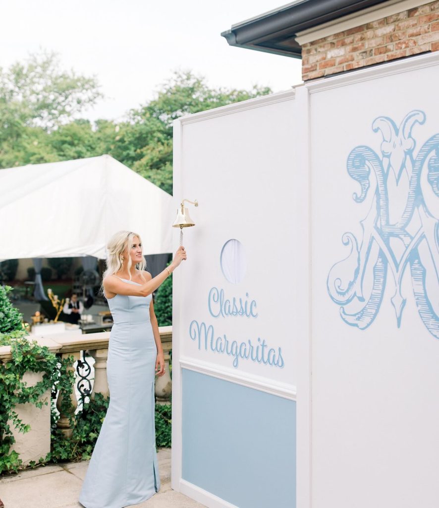 White wedding welcome sign with blue monogram at outdoor venue