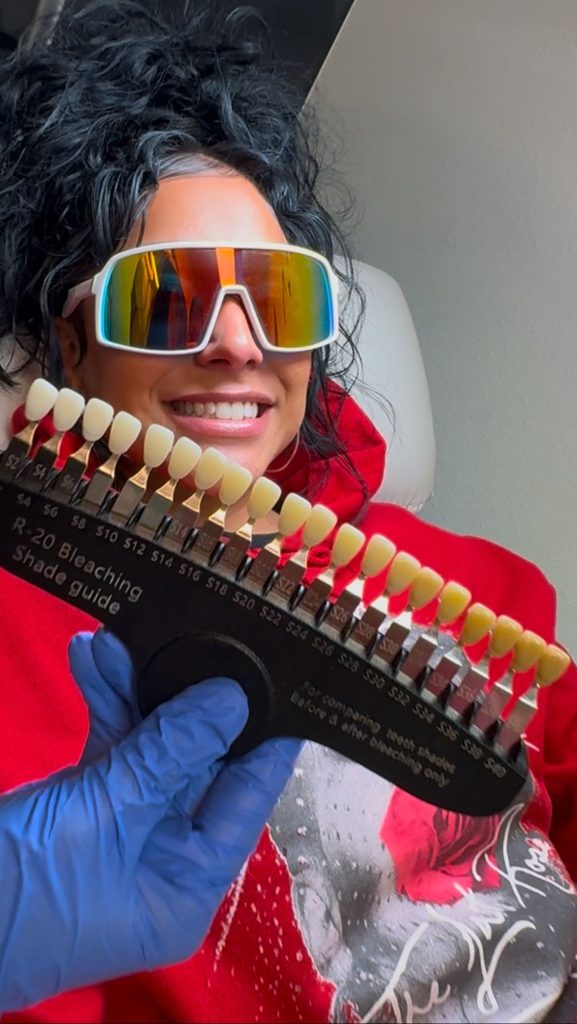 Smiling client wearing protective eyewear while receiving professional teeth whitening treatment