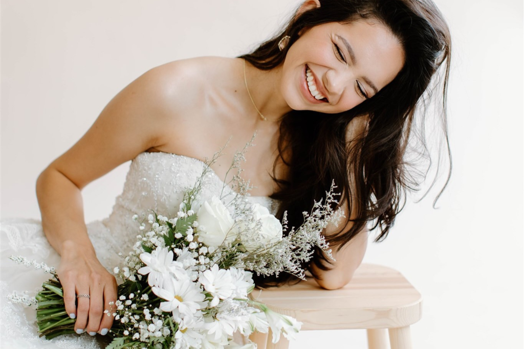 Happy bride in strapless wedding gown with natural bridal makeup and bouquet
