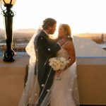 Newlyweds embrace on Hotel Paso Del Norte rooftop at sunset with El Paso cityscape and mountains in background