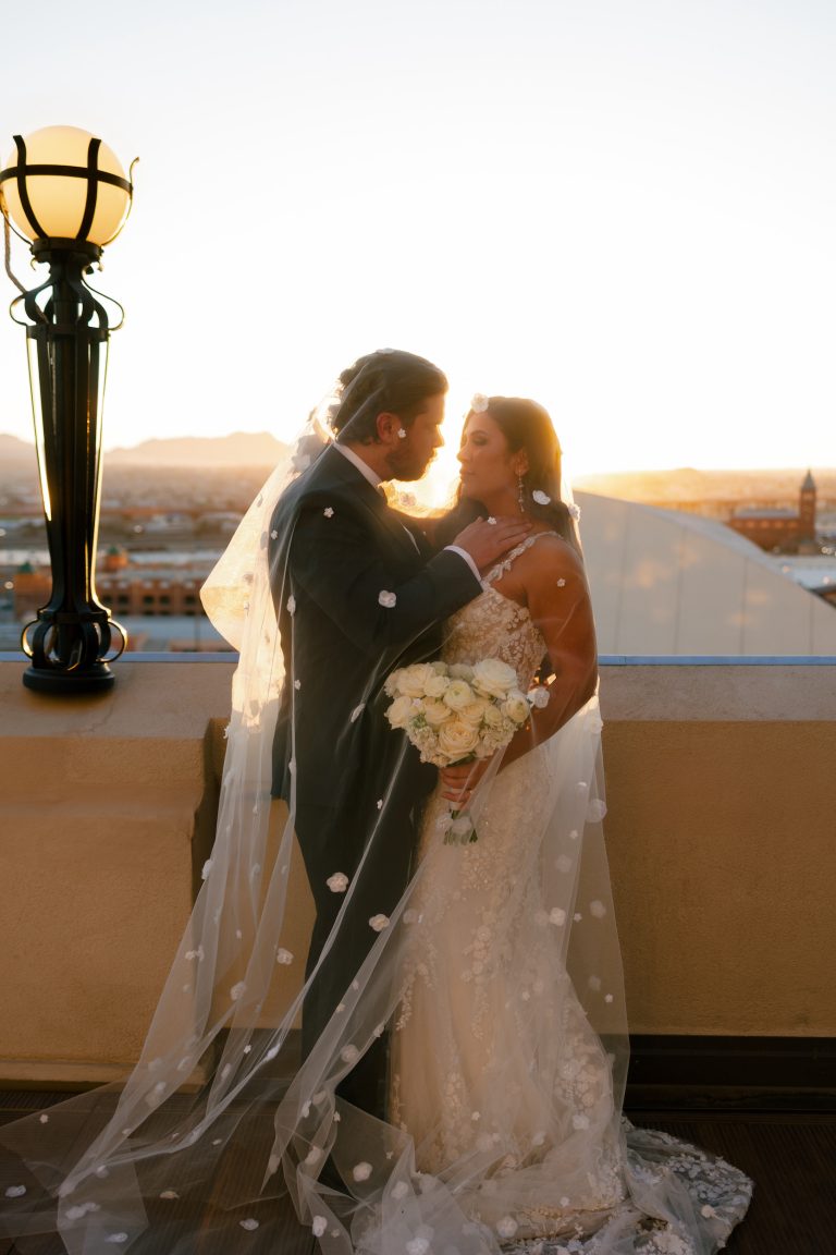 Newlyweds embrace on Hotel Paso Del Norte rooftop at sunset with El Paso cityscape and mountains in background