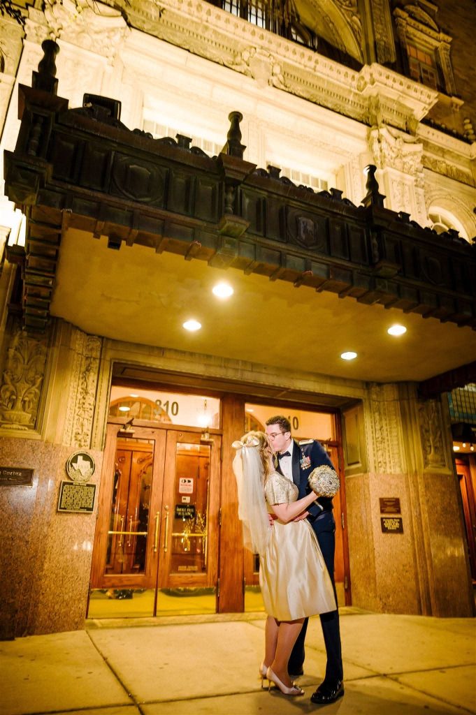 Bride and groom kissing beneath ornate Art Deco balcony and entrance of historic Cortez Ballroom