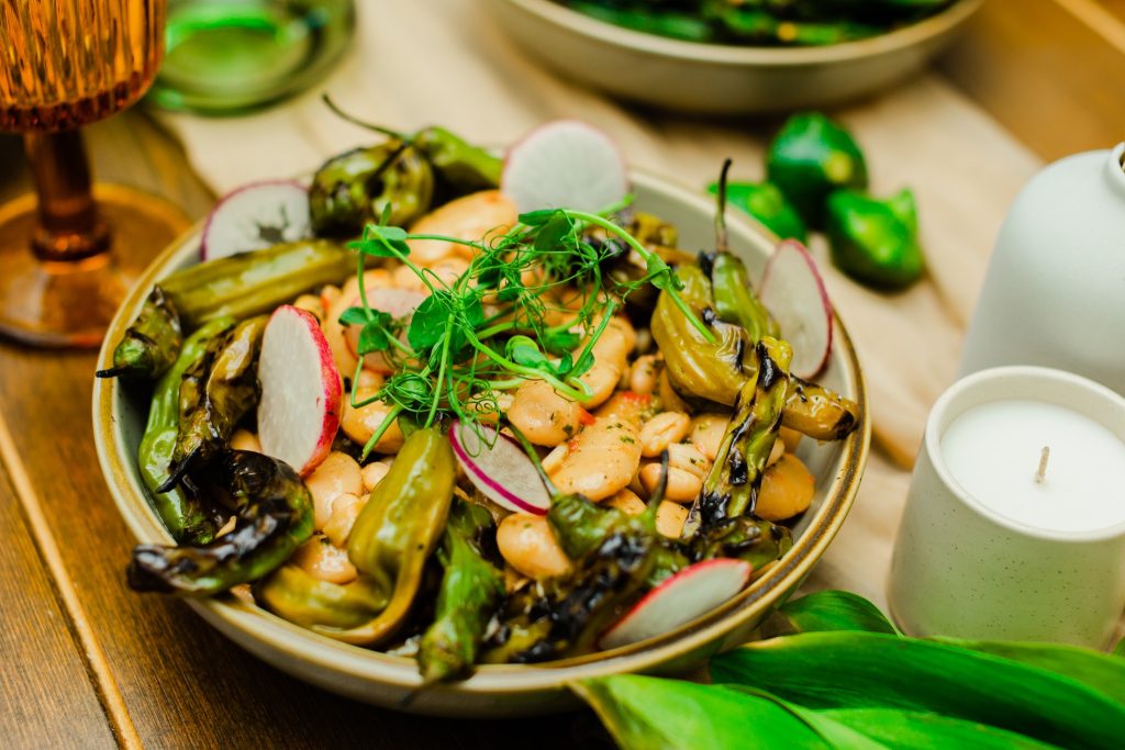Plated dish with grilled vegetables, beans, and fresh radish slices on white dinnerware