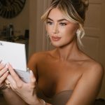 Bride wearing high bun updo with face-framing tendrils and statement earrings reads card