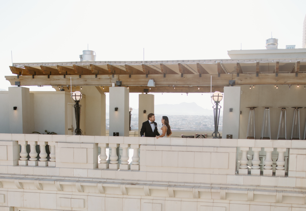 Bride and groom on rooftop terrace with pergola and downtown El Paso skyline views