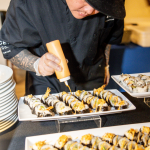 Chef drizzling sauce over artfully arranged sushi platters at wedding reception