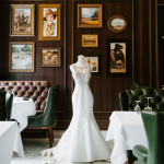 White wedding gown displayed against gallery wall with western artwork and brown leather seating