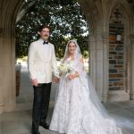 Bride and groom in formal wedding attire standing under stone archway