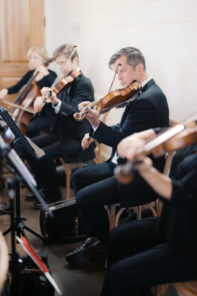 String quartet in formal black attire performing at wedding ceremony with violins and cello